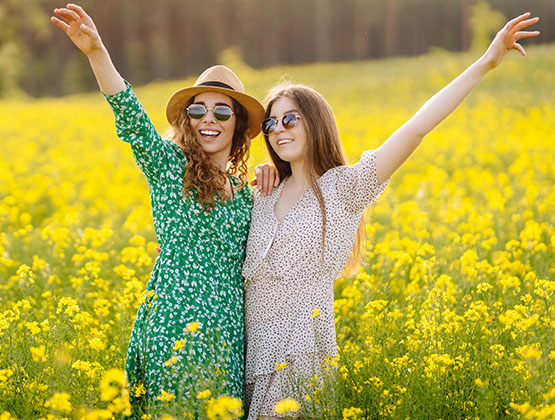 Two joyful women standing in a field of yellow flowers