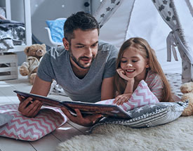 A dad reads a book to his daughter