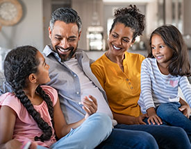 A family of four sitting on a couch together and smiling