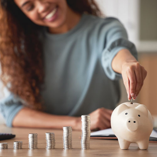 A woman counting coins and putting them in a piggy bank