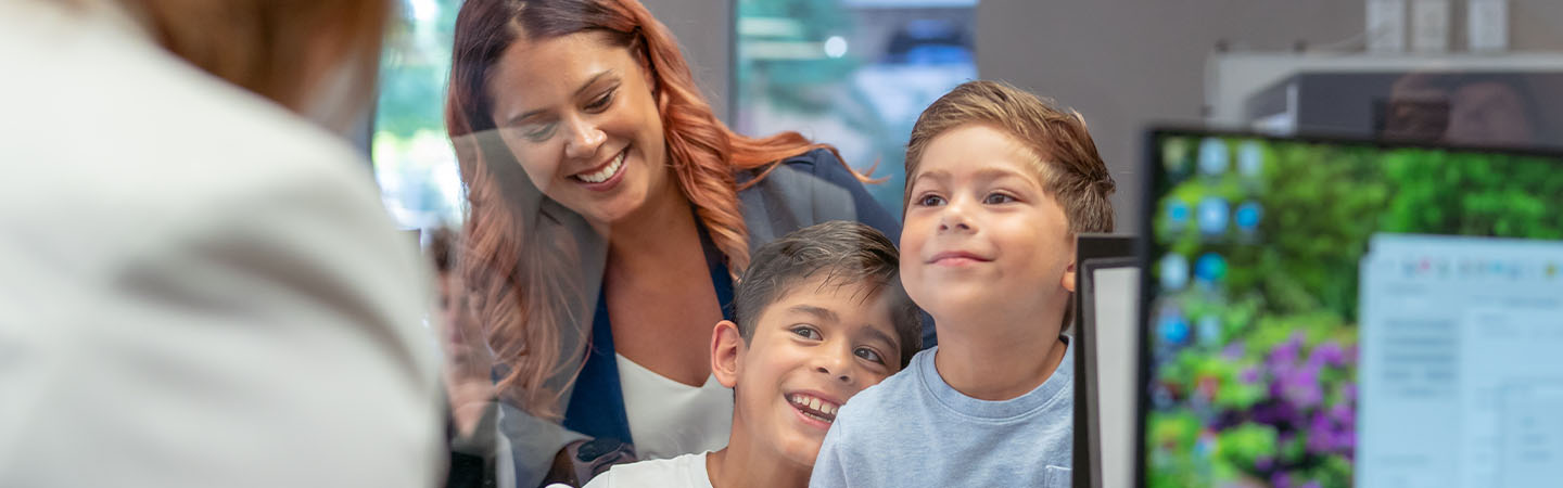 Two boys and their mom at a bank teller window