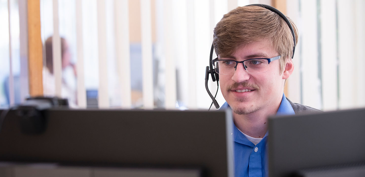 Employee wearing a headset and looking at a computer monitor