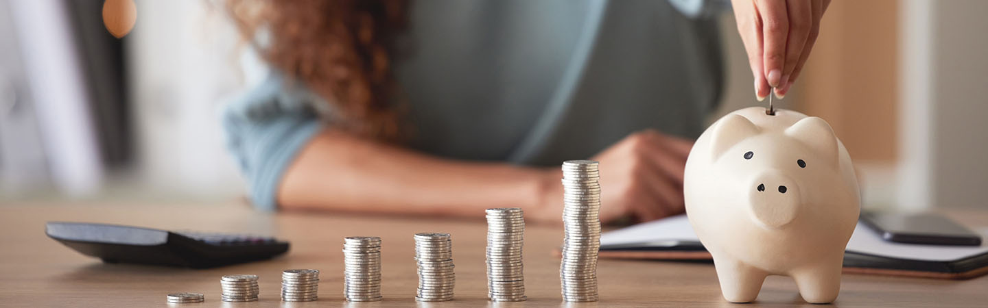 A woman stacking coins and putting them in a piggy bank