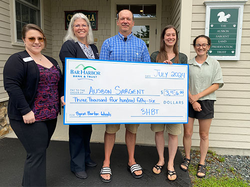 Employees present a donation to Ausbon Sargent Land Preservation Trust