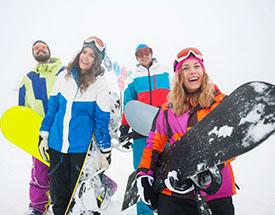 Group of smiling friends holding snowboards in the snow